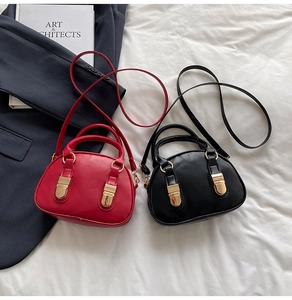 Flat lay of red and black shell bowling handbags with gold buckles on a white fabric
