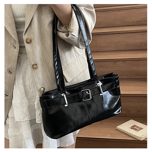 Close-up of black patent leather shoulder bag with silver hardware and polished finish