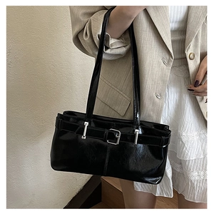 Detail of black glossy shoulder bag with silver buckle and sleek faux leather finish