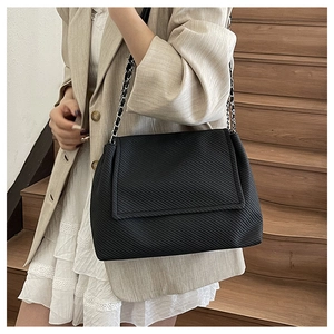 Gros plan d'un sac bandoulière noir avec texture matelassée et bandoulière en chaîne