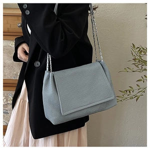 Detail of grey-blue shoulder bag with textured fabric and silver chain on model