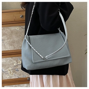 Détail du sac à bandoulière en sergé bleu clair avec chaîne argentée et rabat chic