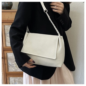Schicke beige Tragetasche mit Webstruktur und silberner Kette an der Schulter des Models
