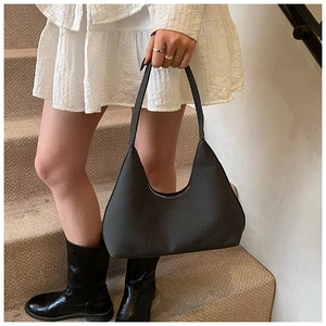 Detailed texture of dark grey woven hobo bag shown being worn by a fashion model