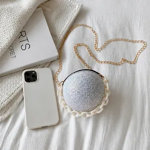 Macro view of spherical silver glitter evening bag with chunky chain and gold strap