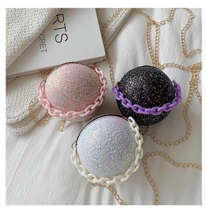Close-up of three spherical glitter handbags in pink black and silver with chain straps