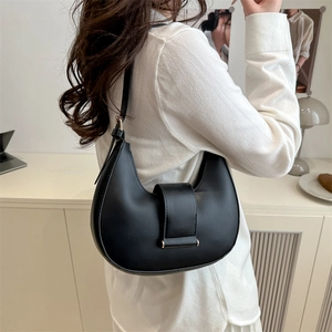 Classic black leather crescent underarm bag worn by model in a minimalist studio setting