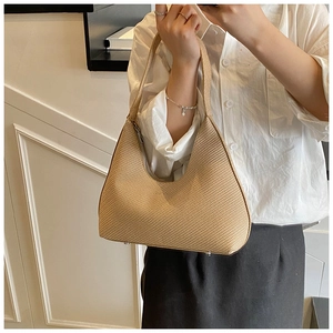 Detail of light brown woven hobo bag showing zipper closure and protective metal feet