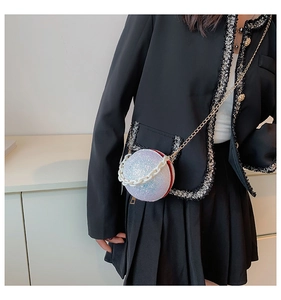 Close-up of spherical iridescent sequin bag with acrylic chain worn with black outfit