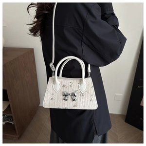 Floral embroidery straw crossbody bag with silver bow accent shown on model back