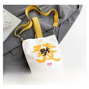 Detail of white canvas fortune bag featuring yellow Fa character and woven strap