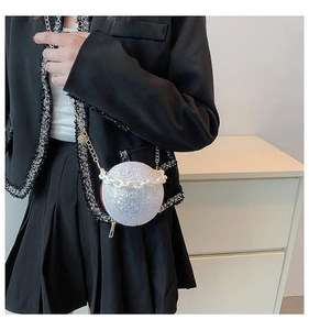 Detailed view of spherical glitter crossbody bag with pearl strap on model's outfit