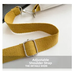 Detail of adjustable yellow woven shoulder strap with silver metal buckle on white bag