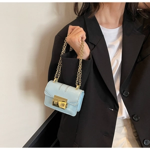 Close-up of mint blue mini square bag with gold chain strap on black blazer outfit