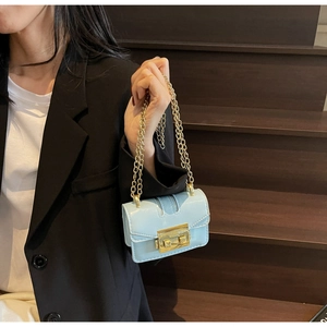 Detail of light blue patent leather mini bag with gold chain strap and metal lock