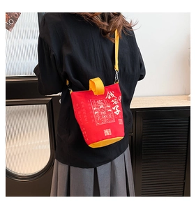 Detail of red canvas bucket bag with yellow straps and lucky Chinese character design