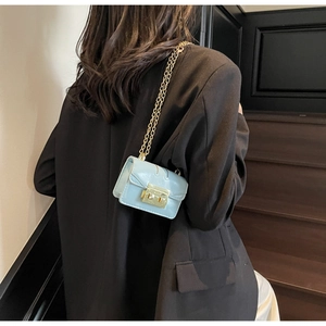 Detail of light blue mini chain bag featuring a textured finish and golden metal lock