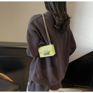 Detail of neon green chain square bag with gold metal buckle on brown waffle outfit