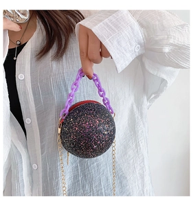 Detail of glitter spherical evening bag with purple acrylic chain and gold strap