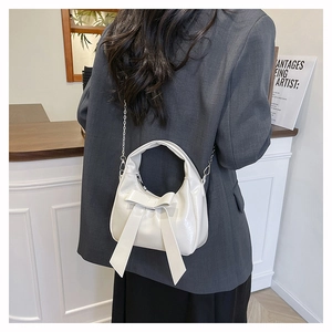 Detail of off-white crescent bucket bag with large bow and silver chain strap
