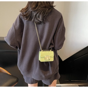 Rear view of a model wearing a mini lime green leather crossbody bag with gold chain strap