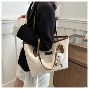 Nahaufnahme der Hahnentritt-Tasche mit braunem Lederbesatz und Plüsch-Anhänger