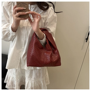 Detail of a dark red woven hobo tote bag with a signature knot handle on the shoulder