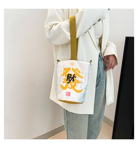 Macro detail of canvas bucket bag featuring lucky calligraphy and wide yellow strap