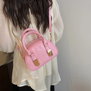Chic pink shell-shaped bowling bag with gold buckle accents shown on model shoulder
