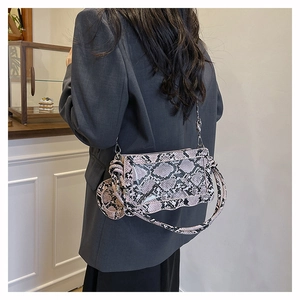 Détail du sac à bandoulière motif serpent rose avec chaîne et petit porte-monnaie rond