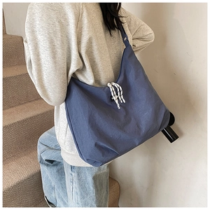 Detail of navy blue canvas crossbody bag with drawstring closure and fashion label