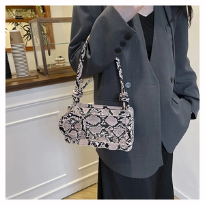 Détail de la texture serpent et de la mini pochette ronde sur le sac à bandoulière
