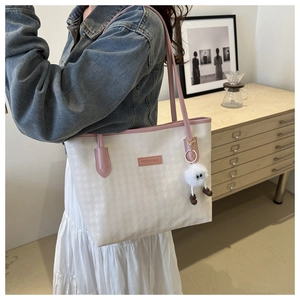 Detail der cremefarbenen Tote Bag mit Hahnentrittmuster, rosa Griffen und Plüschanhänger