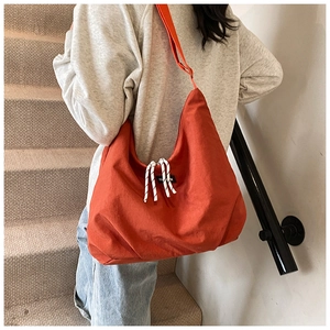 Dettaglio borsa shopper in tela arancione con coulisse e etichetta di moda