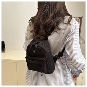 Détail d'un sac à dos noir en velours côtelé avec rayures texturées et doubles poches zippées