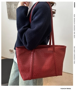 Detail of red woven texture on a large faux leather tote bag with long shoulder strap