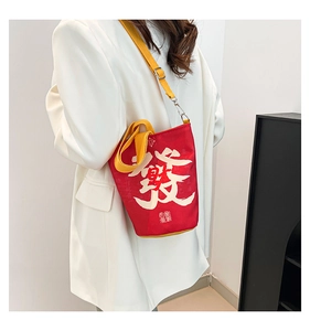 Detailed shot of red canvas bucket bag featuring white calligraphy and yellow straps