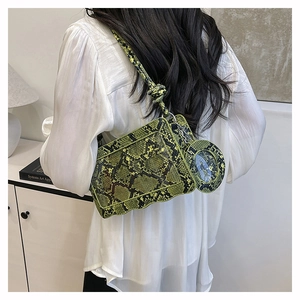Détail du sac à main vert motif serpent avec fond ondulé et accessoire rond