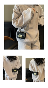 Close-up of minimalist black mini crossbody bag featuring a gold clasp and chain strap