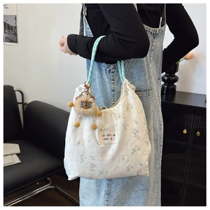 Detailed close-up of floral print nylon tote bag with lion plush pendant and brand label