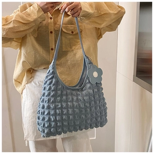 Détail du sac hobo bleu clair à texture bulle avec un accessoire de charme floral assorti
