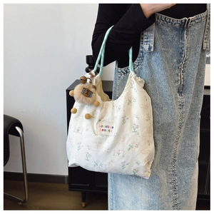 Detail of white canvas tote bag with floral bunny print and blue rope handles