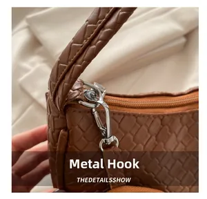 Detailed close-up of the silver metal hook and woven strap on a brown tote bag