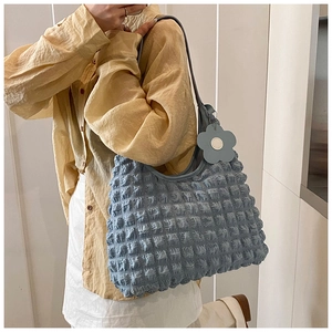 Détail du sac cabas bleu clair à texture bulles 3D avec pendentif fleur sur l'épaule