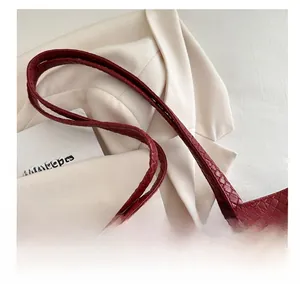 Close-up of deep red woven texture on tote bag with slim shoulder handles