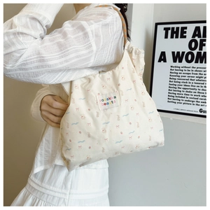 Detail of the colorful cartoon bear print and logo patch on the cream canvas tote bag
