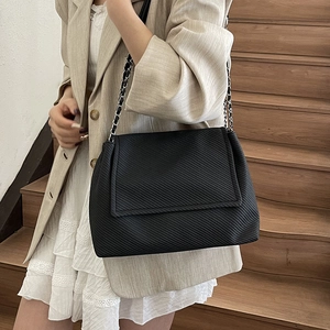 Sac fourre-tout noir minimaliste avec rayures texturées et chaîne en métal porté par un mannequin