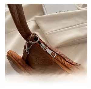 Close-up of smooth metal zipper and brown textured leather on a shoulder bag