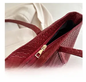 Detail of a smooth gold metal zipper and dark red woven texture on a chic tote bag