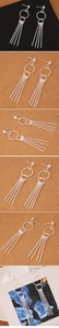 Close-up of silver multilayer geometric rings with long fine metal tassels earrings